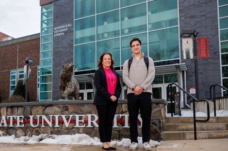 A woman and man stand smiling in front of a Bear Statue