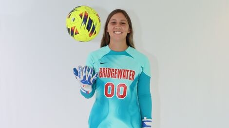 woman smiles holding a soccer ball 