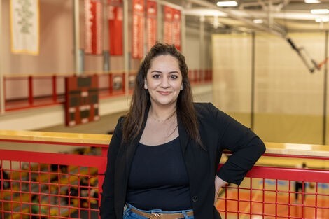 A woman wearing a black shirt stands and smiles at the camera