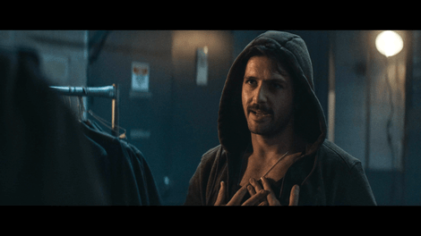 A man wearing a hood talks to another person 