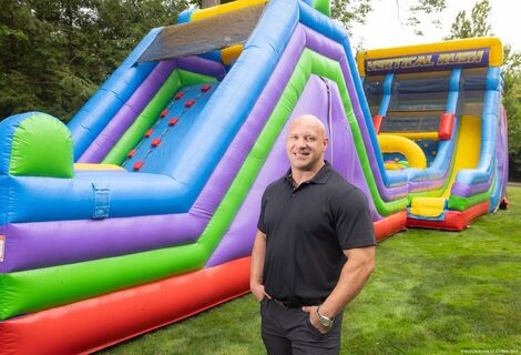 A man stands in front of an inflatable slide 