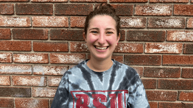 Sara Barry smiles in front of a brick wall