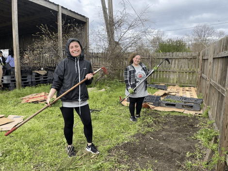 Gwen Gacek, ’27, left, cleaning up the grounds of Common Ground Relief Nursery in New Orleans to make room for raised beds to aid in the survival of the surrounding trees and plants.