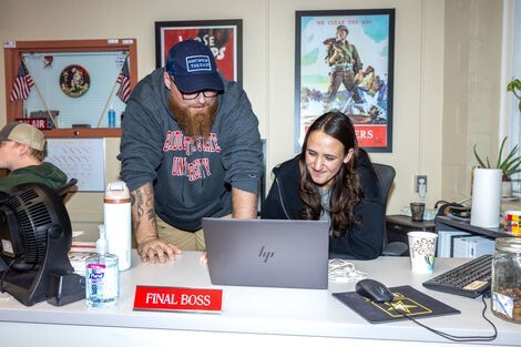 A man and woman look at a laptop together while smiling 
