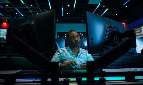 A BSU student working at a dual monitor workstation in the cyber range
