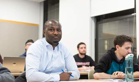4 students sitting at desks in in a graduate class