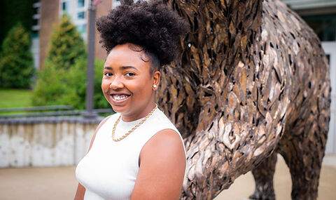 BSU Political Science major Maya Elysse smiling in front of the Rondileau Student Union bear statue
