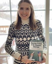 Dr. Jacquelynne Boivin smiling with long light brown hair and wearing a black and white sweater. She is holding her book titled Unpacking Privilege in the Elementary Classroom