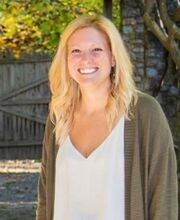 Dr. Amy Mercado smiling with long blonde hair wearing an open taupe sweater over a white v-neck blouse