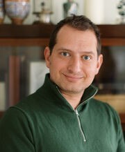 Dr. Seth Meyer smiling with short brown hair and wearing a dark green pullover with zipper neckline