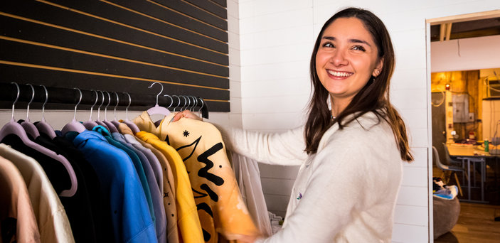 Megan stands in front of clothing rack