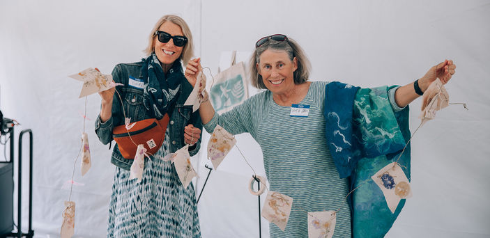 Two people hang artwork at a Senior College event.