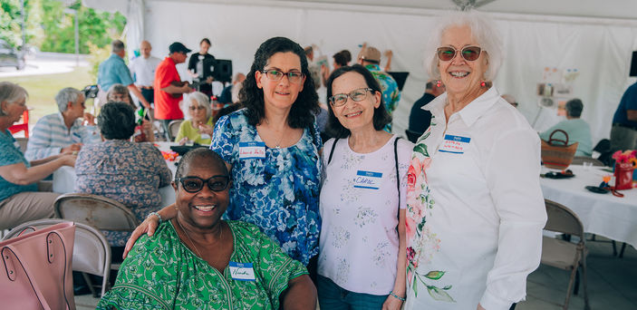 Four people pose for a photo at a Senior College event.
