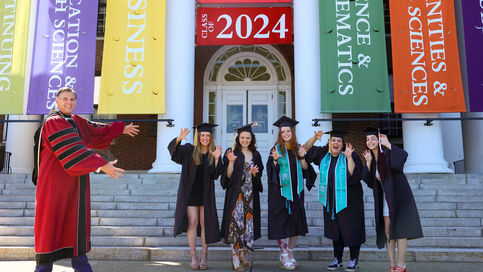 president clark wears graduation regalia and points to 5 seniors posing as bears in graduation regalia