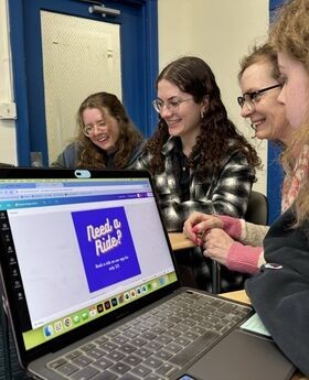 A group of students around a laptop as they work on writing a grant for CUBEs