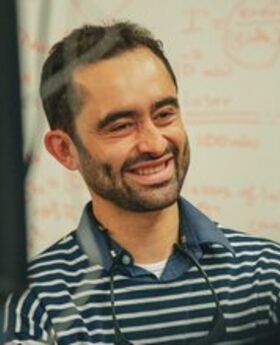 Samuel Serna Otalvo smiling in front of a white board