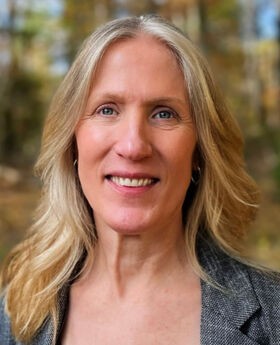 Dr. Darcy Boellstorff smiling with long blonde hair and wearing a gray blazer over a black top