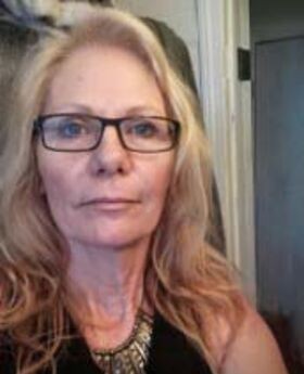 Dr. Nancy Monroe with long blonde hair and wearing black rimmed glasses, a sleeveless v-neck top and a chunky metal necklace