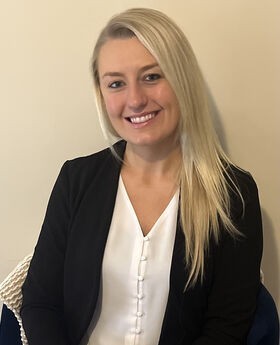 Chelsea Pilling smiling with long straight blonde hair wearing a v-neck white blouse and a black blazer