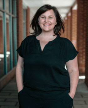 Colleen Kelly Poplin smiling with medium length dark brown hair wearing a v-neck black top
