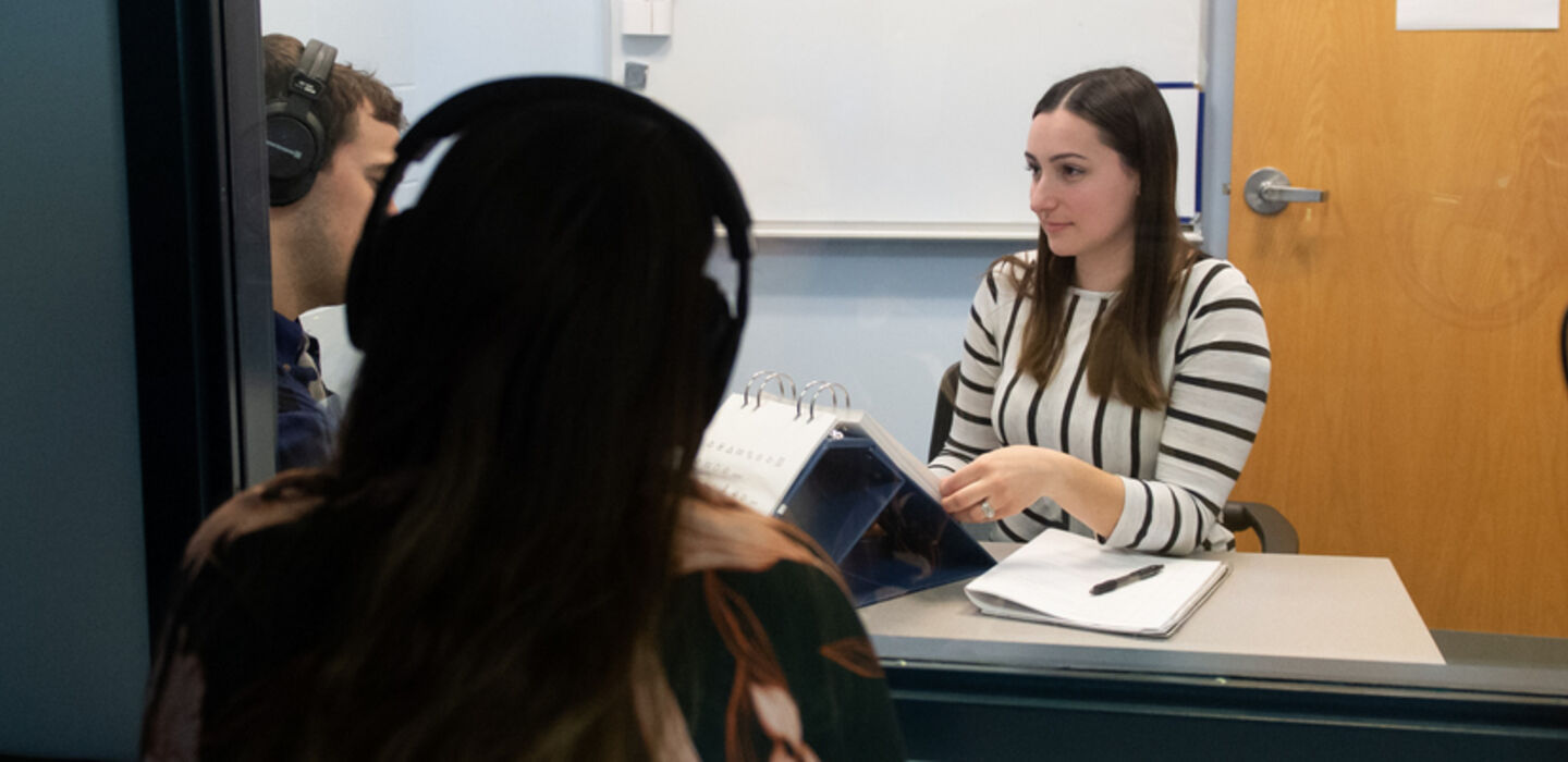 a student working with a client while a supervisor watches through a 2 way mirror