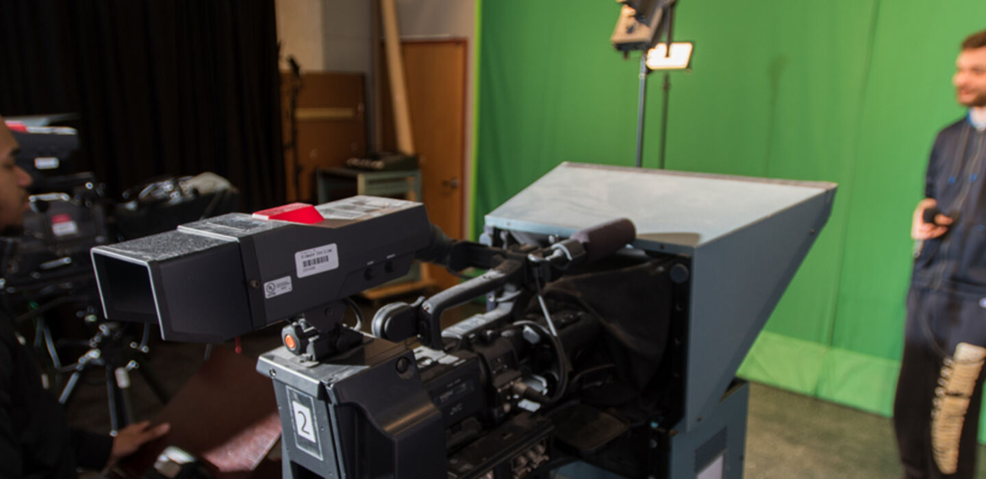 3 students operating tv cameras with another in front of the camera talking into a microphone